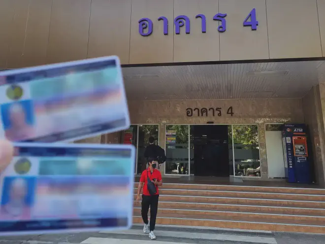 An image of a man holding a Thai drivers license outside the Department of Land Transport Bangkok.