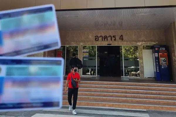 An image of a man holding a Thai drivers license outside the Department of Land Transport Bangkok.